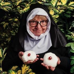 A nun holds two buns with a saucy look