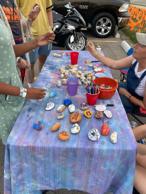 Rally participants gather around a table, painting rocks with peace-centered designs