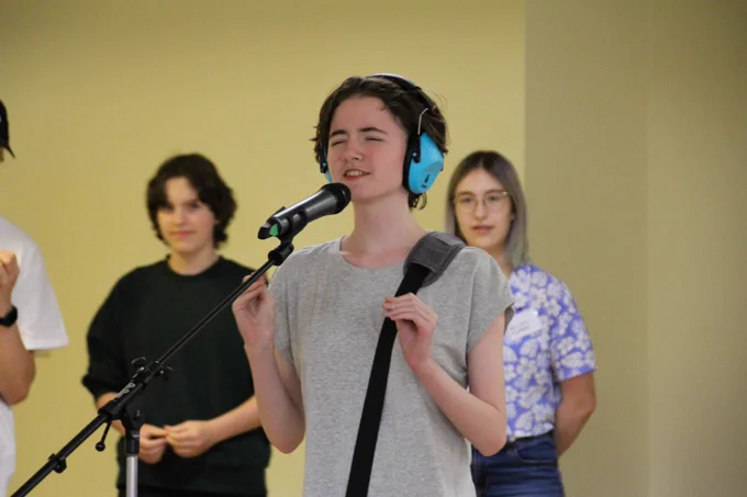 A camper stands at a mic, eyes closed, during a performance.