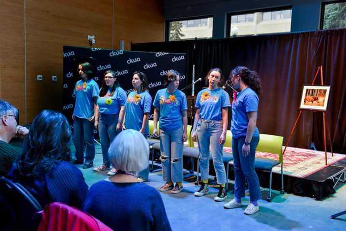 Members of the Spoken Word Youth Choir stand beside each other in a line during a performance. Photo Credit: Alexis Marie Chute/Edmonton Poetry Festival.