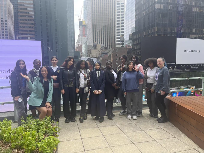 Students pose in a large group on a rooftop in Times Square. 
