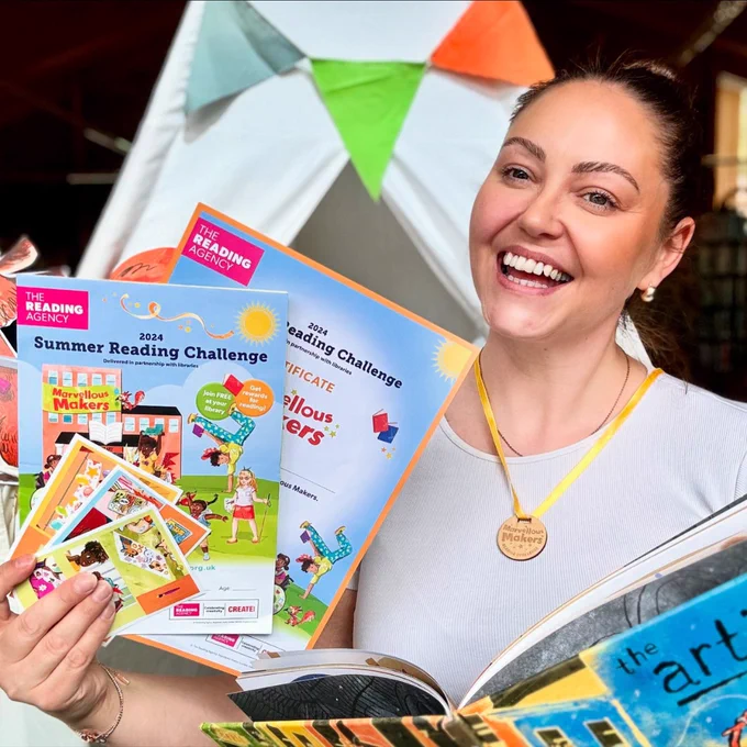 Library staff member holding Summer Reading Challenge resources