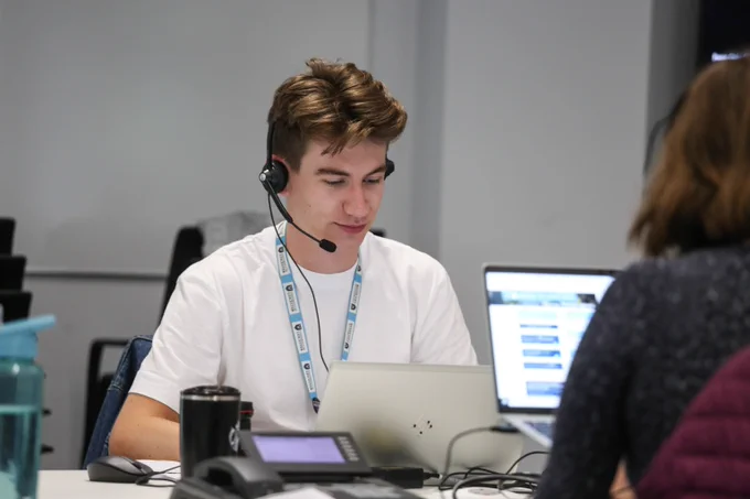 Two of our amazing call handlers sat at laptops, wearing headsets