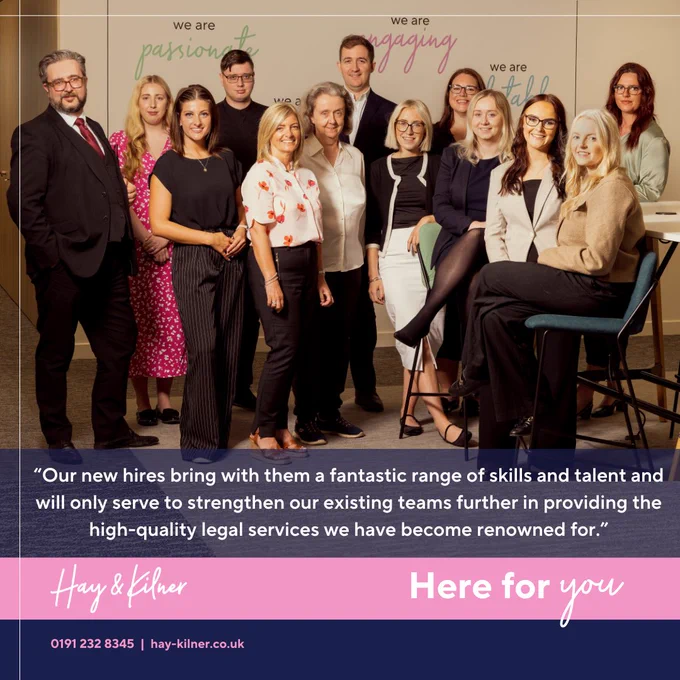A photograph of 13 of Hay & Kilner's newest recruits. They are stood and sat in front of a wall in Hay & Kilner's offices. At the bottom of the picture is a semi-transparent navy blue strip containing a quote from the article referred to the post, which reads "Our new hires bring with them a fantastic range of skills and talent and will only serve to strengthen our existing teams further in providing the high-quality legal services we have become renowned for." Underneath this is a pink strip, with Hay & Kilner's logo in white on the left hand side and "Here for you" written in white on the right hand side.