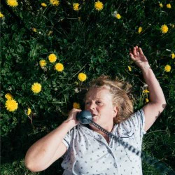 A woman on the phone, lying on grass
