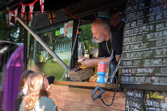 A man leaning out of a food truck taking an order from two people at Sandwich Food & Drink Feastival (by Zoom Events). 