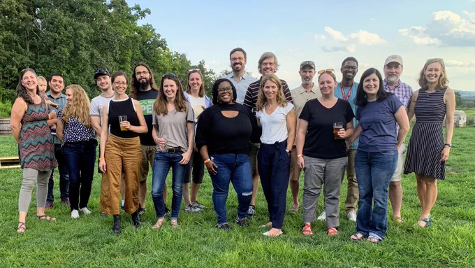 A group of 18 ( 1 cute kiddo of) Virginia Tech Biological Sciences faculty members pose together for a picture on the back lawn at Eastern Divide Brewery in Blacksburg, VA
