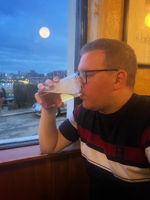 Josh at The Free Trade Inn drinking a pint with the full moon in the background
