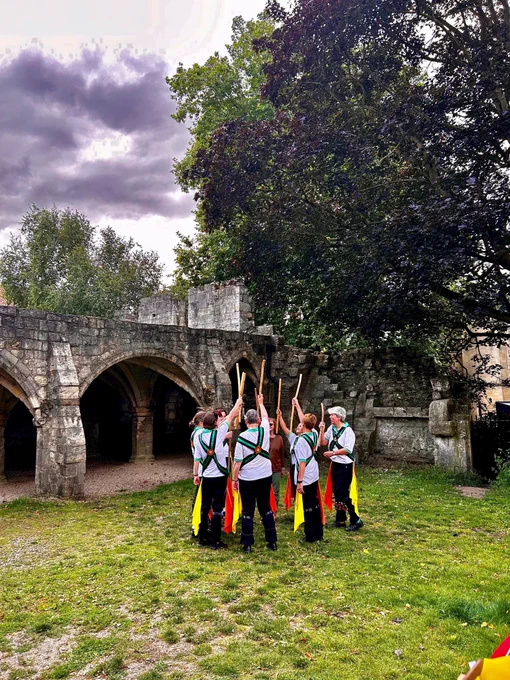 Morris Dancers from Acorn Morris holding Morris Dancing stick together in the air in a peaked fashion the dancers are stood in a circle 