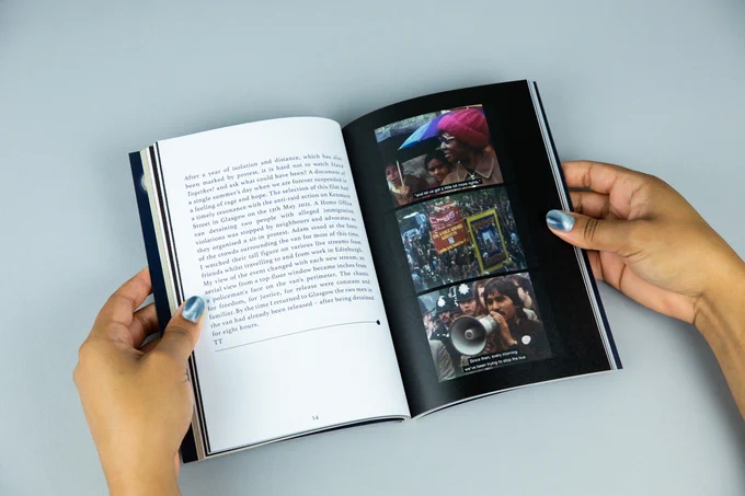 A small book being held open. The left page is white with black writing and the right page is black with three colourful film stills in a column. The stills show people gathering holding umbrellas, people marching with colourful trade union banners and someone speaking through a megaphone while a group of police in traditional style helmets stand behind them. The hands holding the book have shimmering silver nail polish.