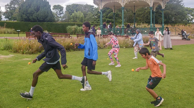 Photo of six people of varying ages competing in a spoon-and-egg race in Saughton Park