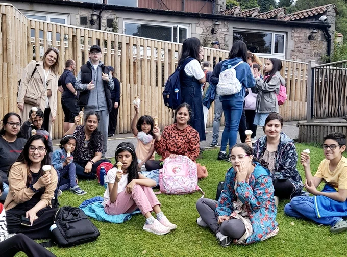 Group photo of Women's Collective members and staff—many holding up ice cream cones—at Edinburgh Zoo