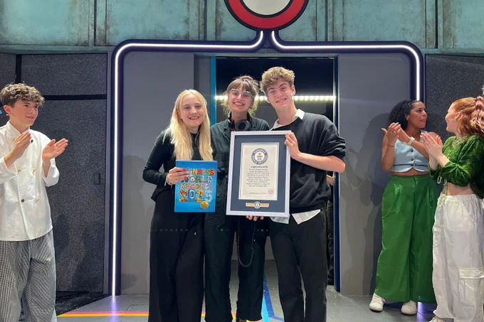A photo showing a group of performers on a stage, holding a plaque for the Guinness World Records