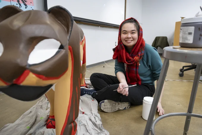 Temple student Anh Thuy Minh Pham sitting on the floor painting statue.