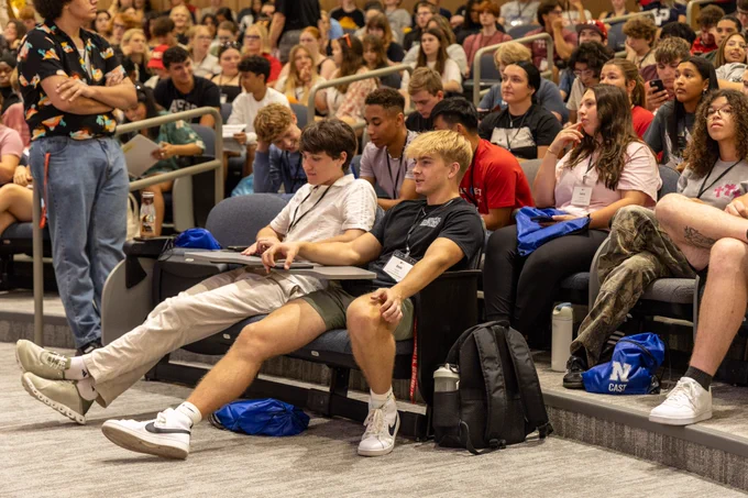 Students sitting in the front row in a large lecture hall. 