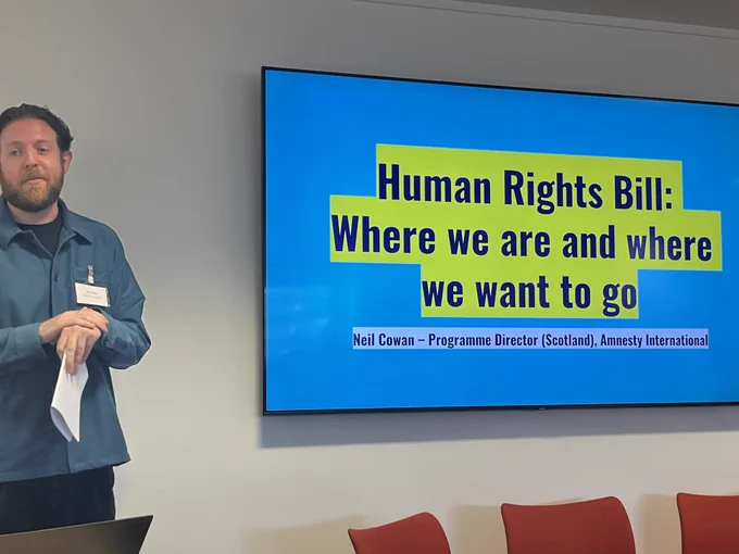 Neil speaking in front of a Amnesty Scotland slide