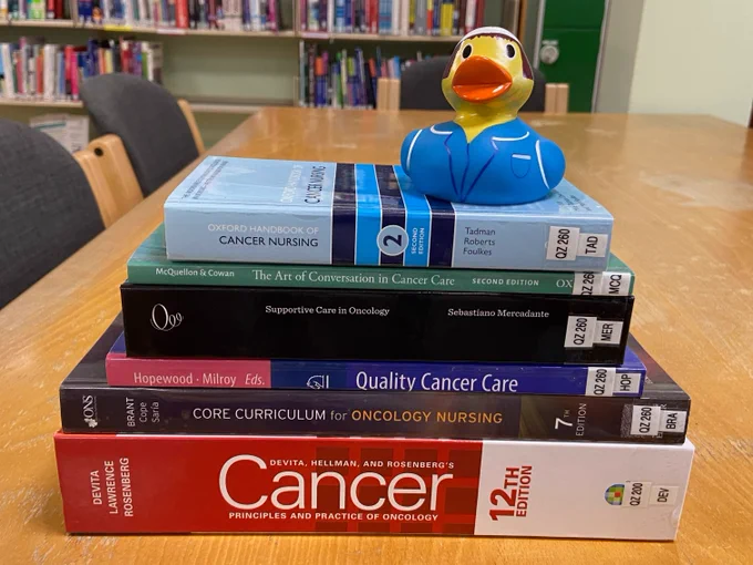 Stack of cancer care and oncology books.