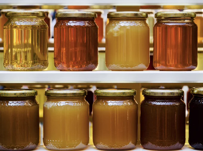 2 lines of jars of honey, all with different colours and consistencies. 