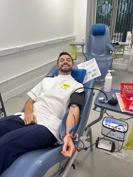 A defence apheresis nurse smiles while donating blood 