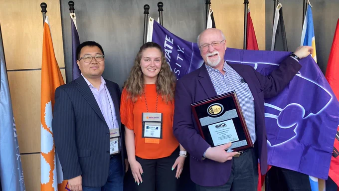 Brad Kramer poses with his award next to a K-State flag.