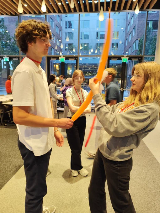 Two Red Team Scholars working together to fix a balloon for the current engineering challenge