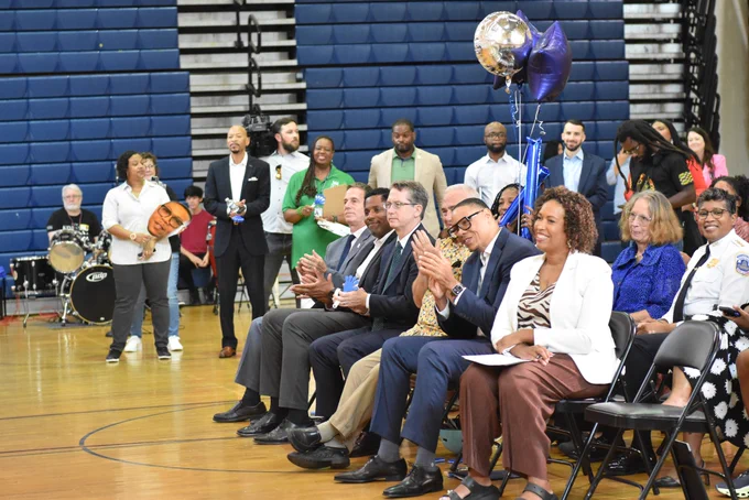 Mayor Bowser, Chancellor Ferebee, Councilmember Frumin, City Administrator Donahue, Director Hunter, Deputy Mayor Kihn, Chief Smith, and General Counsel Cavendish sit together in Alice Deal Middle School's gymnasium.