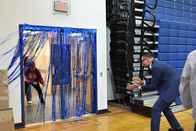 Chancellor Ferebee applauds Alice Deal Middle School's educators right before they walk through a doorway lined with blue streamers.