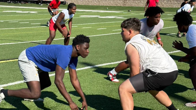 Lincoln High School football players are lined up in offensive and defensive positions during practice on the football field