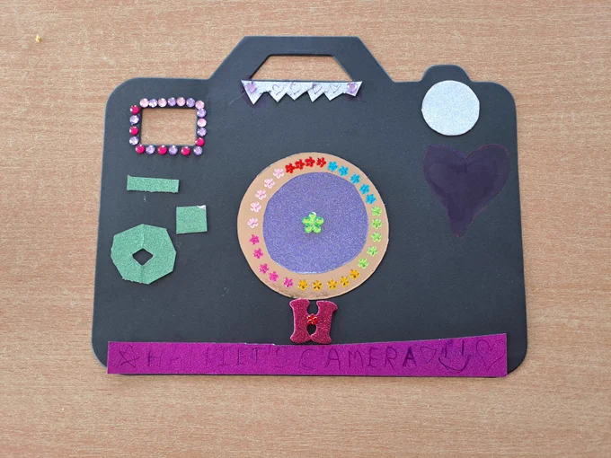 An example of a silhouette of a camera that has been decorated with sequins and paper like a collage