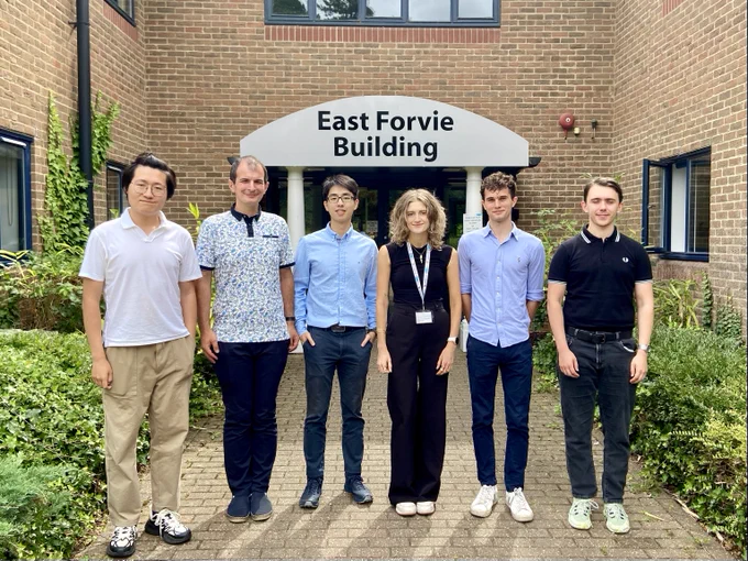 Photo of 6 summer interns - all standing outside in front of building, looking at the camera. 