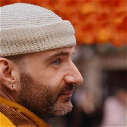 A man in a white beanie looks sideways