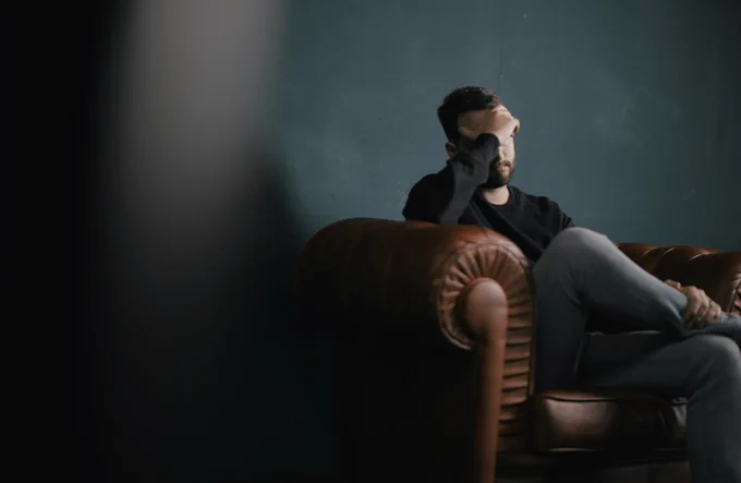 Young man sitting on sofa with head in hands