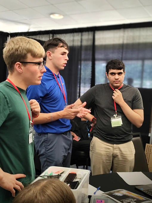 WAS Scholars standing up, discussing about the mission planning around a table.