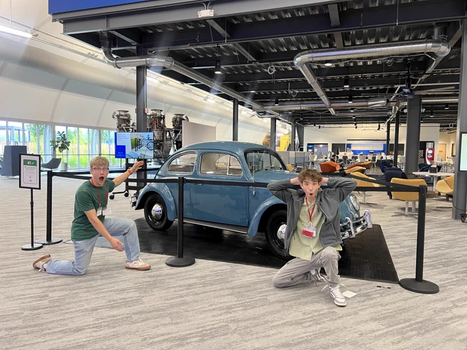 Two Red WAS Scholars taking a picture in front of a car at Blue Origin.