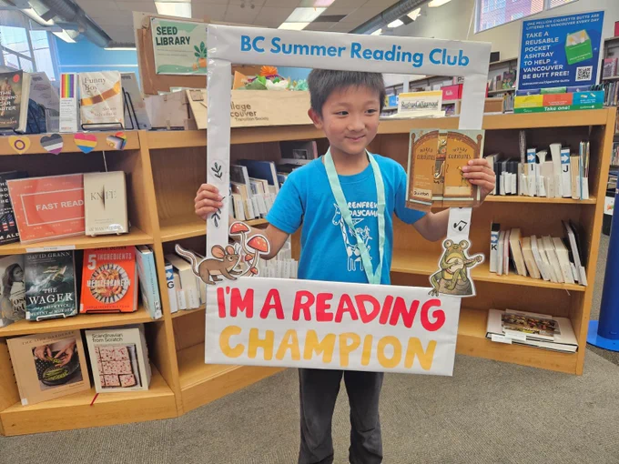 A child is holding a frame that says BC Summer Reading Club
I'm a reading champion. 
