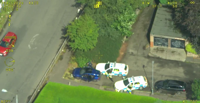 Image of 2 police cars and officers chasing suspects.