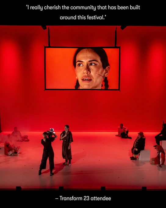  Characters stand on a red lit stage with a big screen behind 