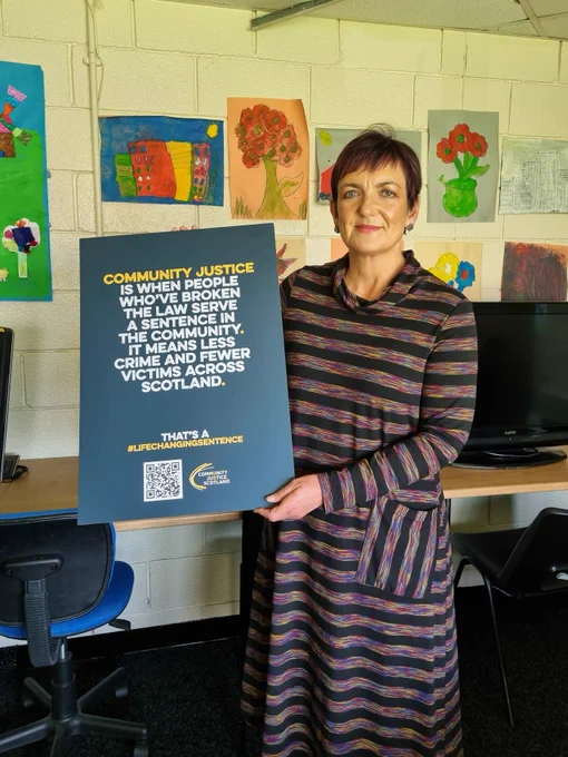 Angela Constance, Cabinet Secretary for Justice, holds a sign that reads: 'Community justice is when people who have broken the law serve a sentence in the community. It means less crime and fewer victims across Scotland'