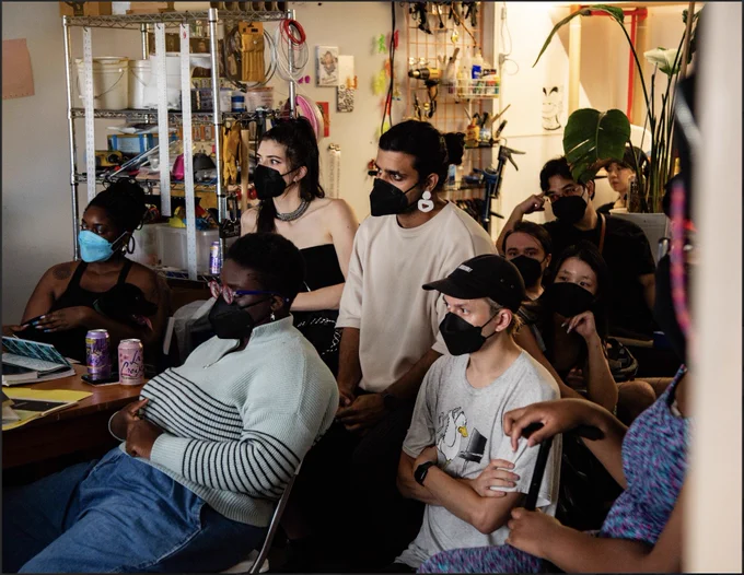 Photo of party assistants, masked, looking at something in front of them