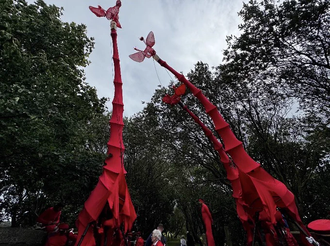 Giant red giraffe puppets in a scenic location.