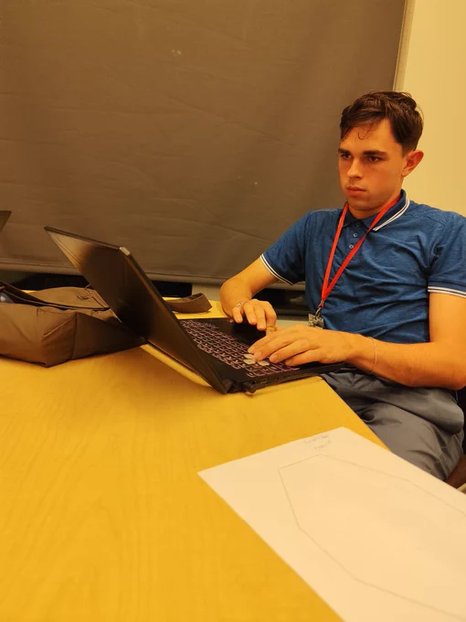 WAS Scholar working at table, typing on laptop.