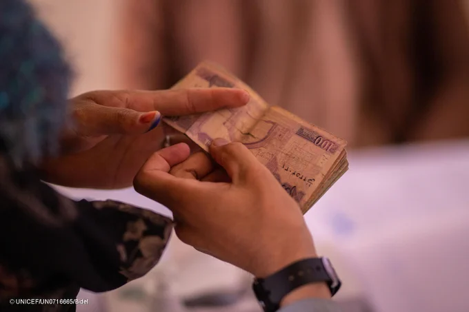 A close-up of a transaction, with one person handing over money to another; only the hands and the banknotes are visible.
