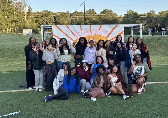 Group of seniors in front of the Senior Sunrise backdrop smiling