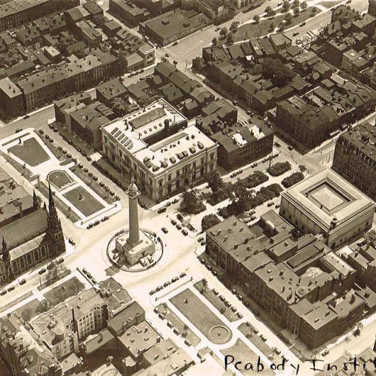 Sepia-toned aerial photo of buildings, an obelisk, and a park in 19th-century Baltimore. 