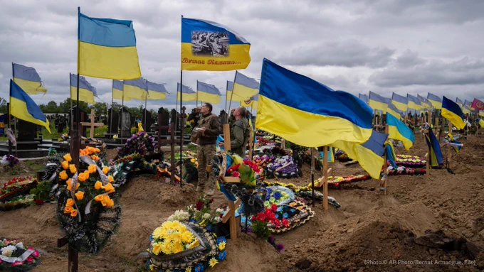 Two national guard soldiers drink a shot to honor the memory of two late soldiers in Kharkiv cemetery, eastern Ukraine, Sunday, May 22, 2022. (AP Photo/Bernat Armangue, File)