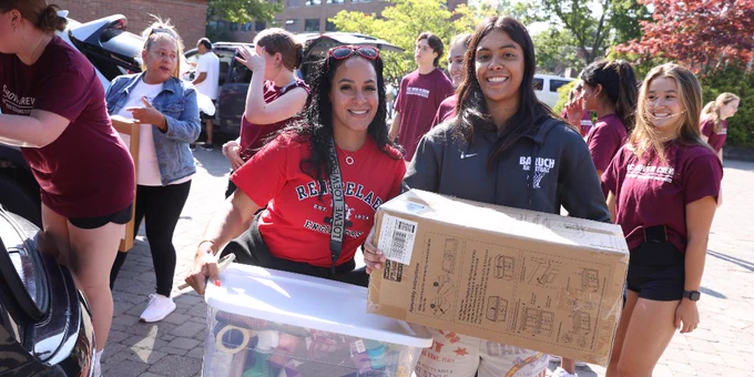 Group of students in RPI apparel smiling and helping carry boxes during first-year move-in day.
