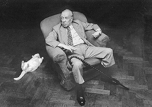 Black and white photo of Jorge Luis Borges in an armchair with a cat. 