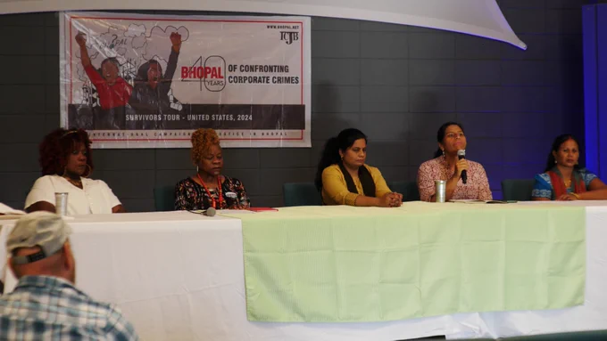 Five panelists sit in front of a #Bhopal40 poster in Lake Charles, LA