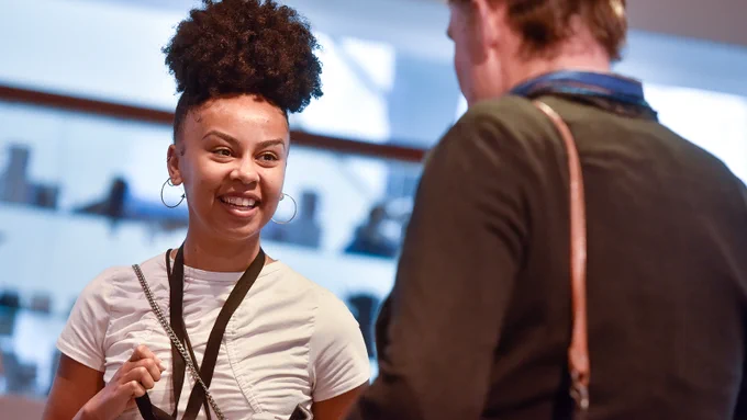 A person smiles while talking at an MA conference