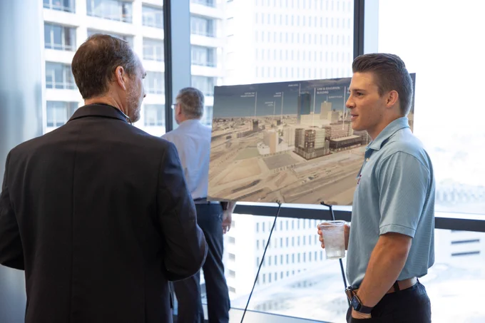 Individuals chat in front of a rendering of the Texas A&M-Fort Worth campus
